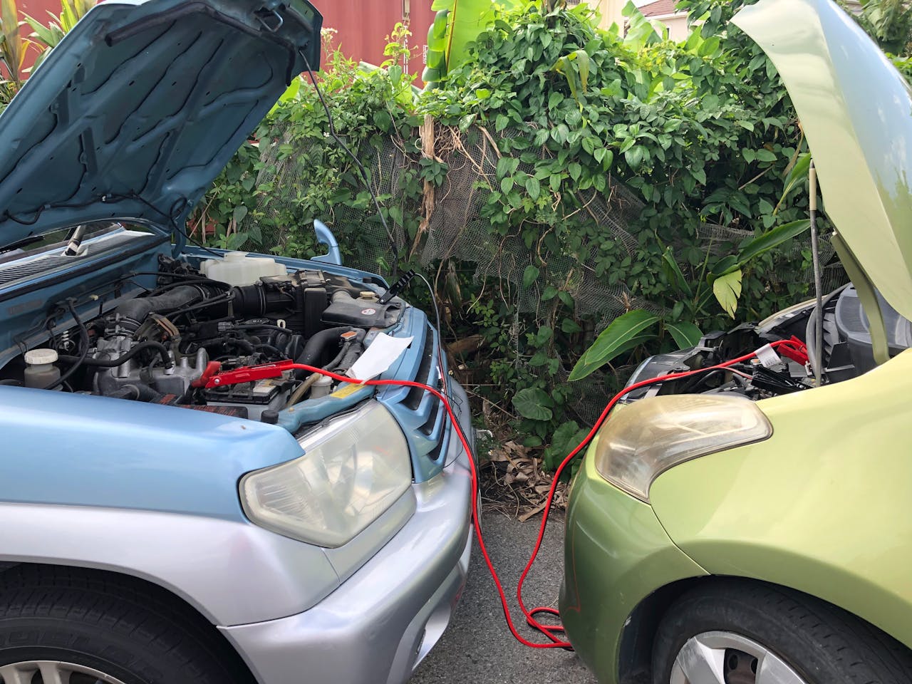 gallery-6 Two cars connected by jumper cables in a parking lot for a battery charge.