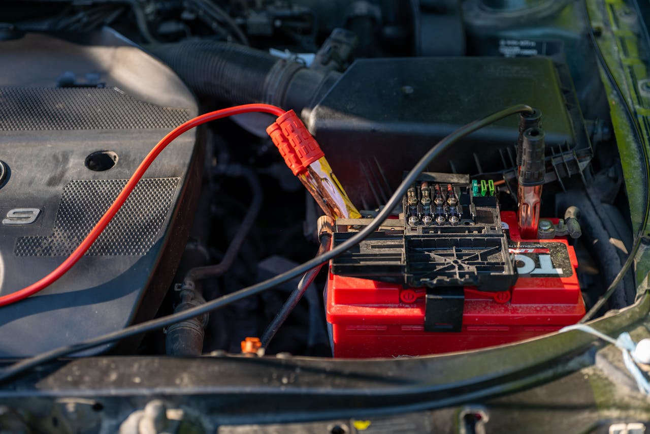 hero-img-02 Close-up of a car battery with attached jumper cables in an engine bay.
