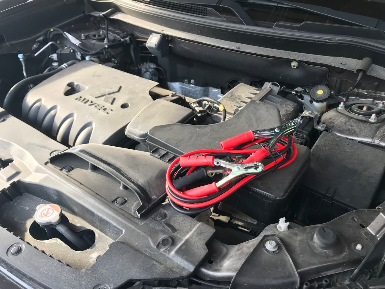 gallery-3 Detailed view of a car engine with red jumper cables, ideal for automotive themes.