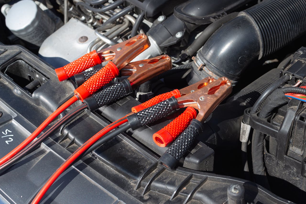 gallery-4 Close-up of car engine with attached jump starter cables, showing detailed mechanics.