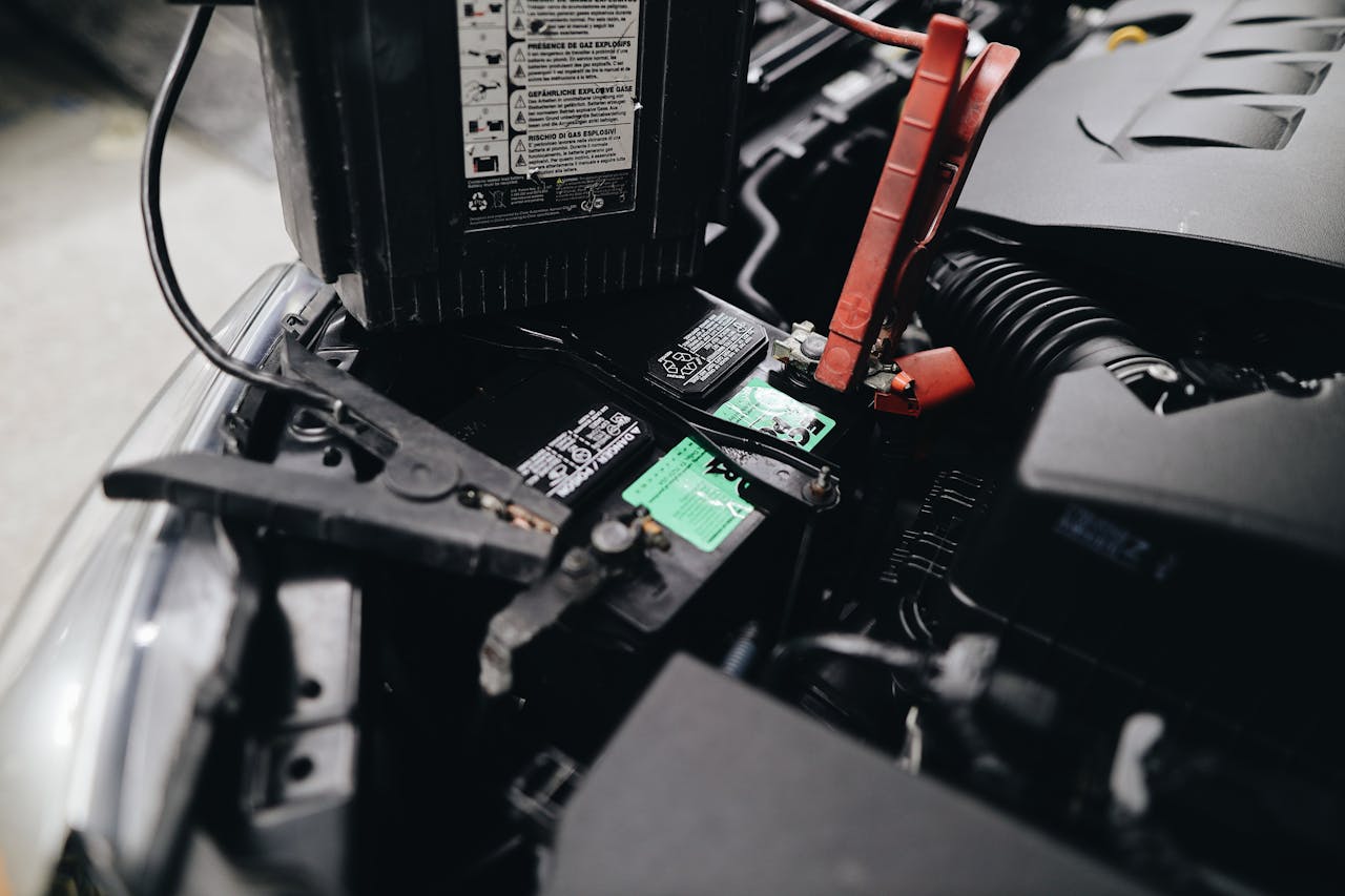 gallery-5 Detailed view of a car battery being jump-started with cables in an engine bay.