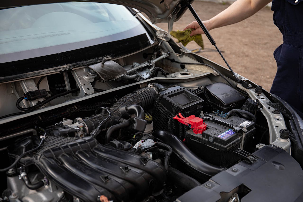 why-choose-us Mechanic inspecting car engine bay and battery during routine maintenance.